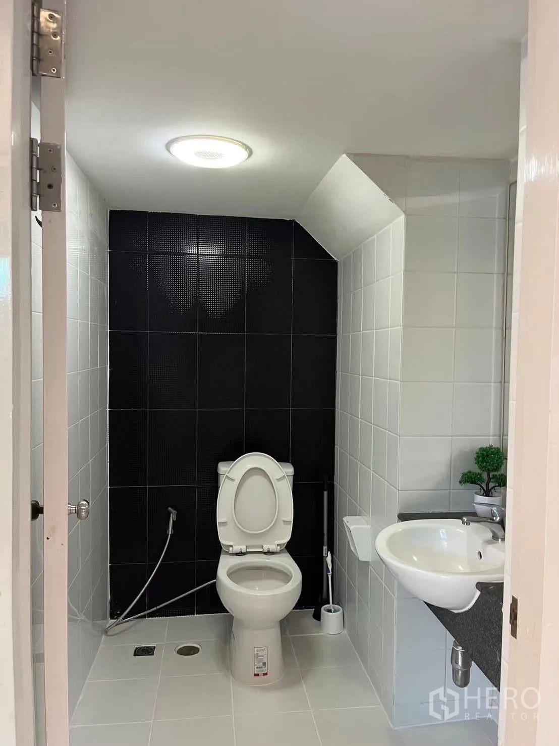 Townhouse for rent in Suan Luang, Bangkok - Downstairs powder room with white fixtures and a black accent wall.