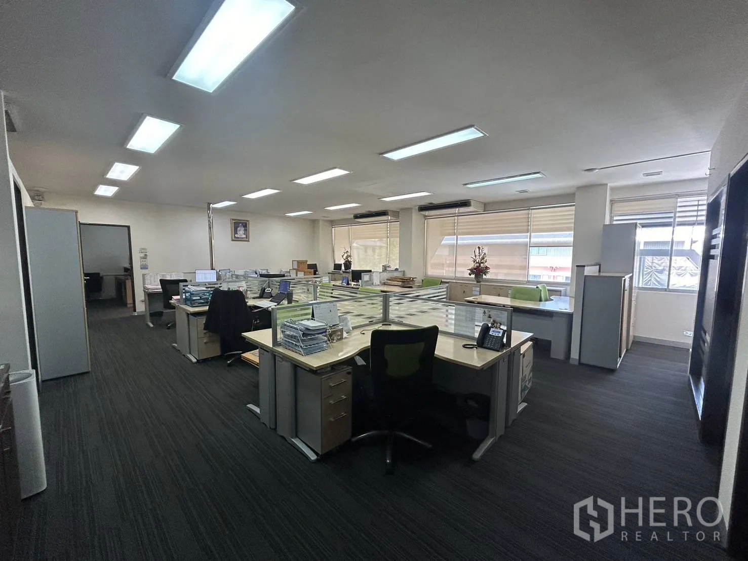 Office Space for rent - Open-plan office floor with multiple workstations, carpet flooring and large windows for natural light.