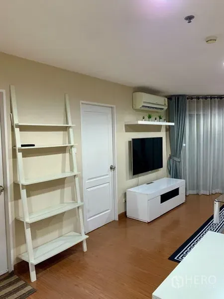 คอนโด ให้เช่าในHuai Khwang, Bangkok - ห้องนั่งเล่นสว่าง ติดทีวีผนัง ตู้วางทีวีสีขาว ชั้นวางแบบบันได แอร์ และผ้าม่านโปร่ง