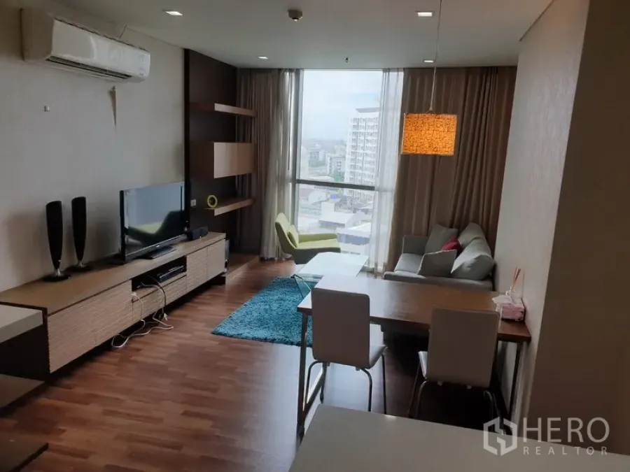 公寓 出租在Watthana, Bangkok - 明亮的客餐厅，落地窗城市景观，沙发、电视柜与木地板。