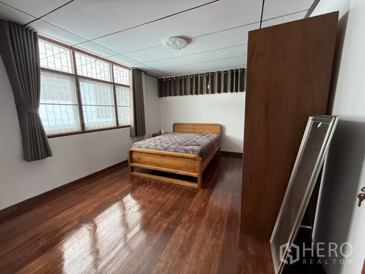 Detached House for rent in Phra Khanong, Bangkok - Spacious bedroom with polished wood floor, bed and large windows.