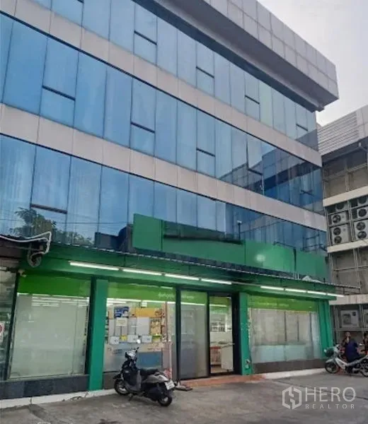 Warehouse for rent in Suan Luang, Bangkok - Front elevation of blue-glass commercial building with green awning above the entrance.