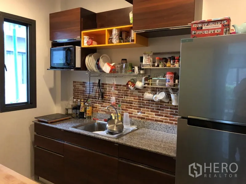 Detached House for rent in Saphan Sung, Bangkok - Functional closed kitchen with granite countertop, brick backsplash and upper cabinets.