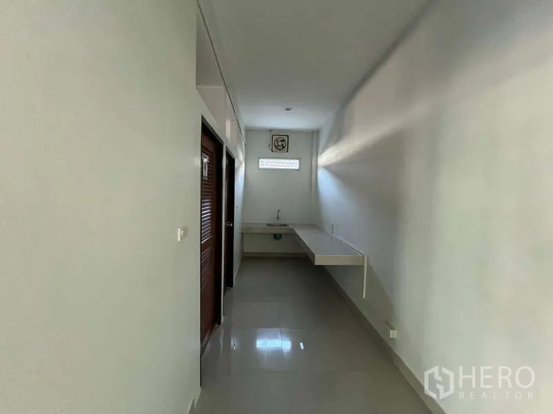 Warehouse for rent in Prawet, Bangkok - Clean corridor with a sink and restroom doors inside the office area.