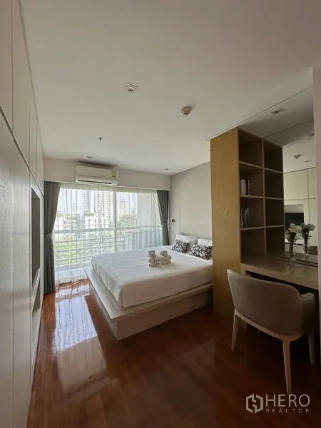 Apartment for rent in Khlong Toei, Bangkok - Bedroom corner with desk and shelving divider facing a large window.