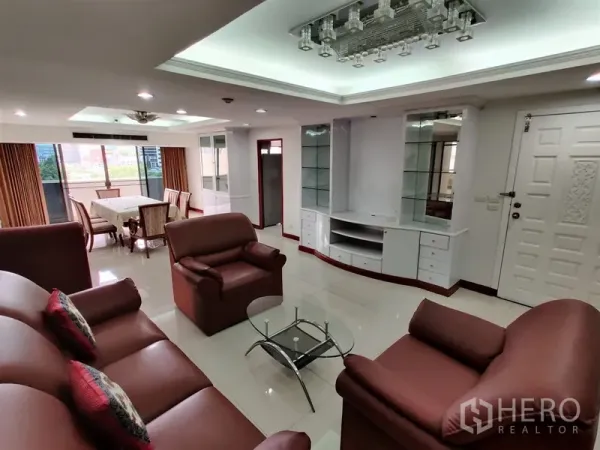 Condominium for rent in Watthana, Bangkok - Spacious living and dining area with leather sofa set, glass coffee table, built-in media cabinet and balcony windows.