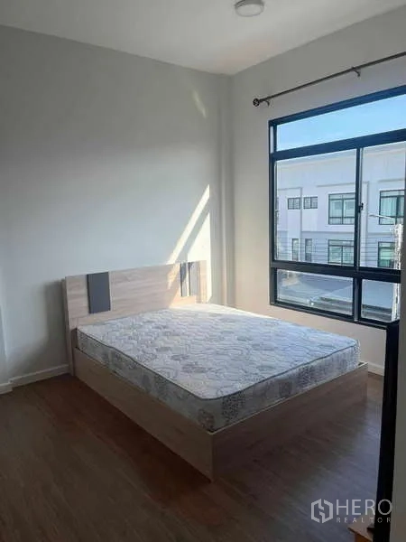 Townhouse for rent in Suan Luang, Bangkok - Corner bedroom with double bed, big windows and natural light on wood floors.