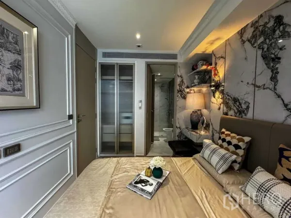 Condominium for rent - Cozy bedroom with marble feature wall, built‑in wardrobe and doorway to ensuite bathroom.