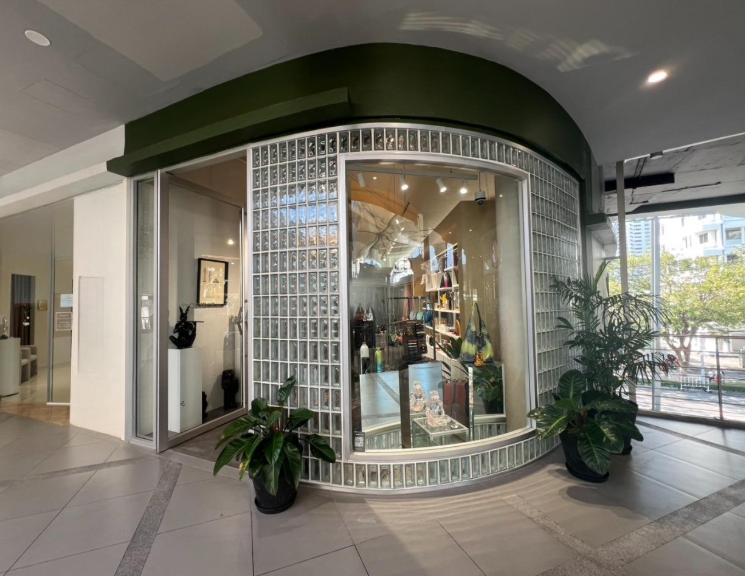 Retail Space for rent in Khlong Toei, Bangkok - Curved glass-block storefront with a large display window and potted plants in a Sukhumvit retail unit.
