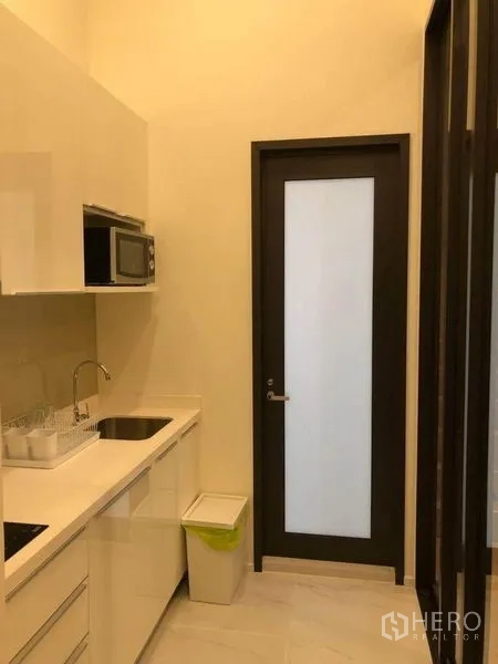 公寓 出售在Ratchathewi, Bangkok - 走廊式厨房，配电磁炉、微波炉与磨砂玻璃门。