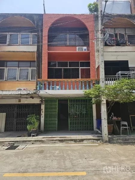 Shophouse for rent or sale in Phra Khanong, Bangkok - Three-story shophouse facade with balcony and green security gate on a quiet Phra Khanong street.