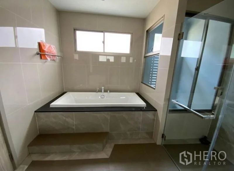 Detached House for rent - Bathroom featuring a built-in bathtub on a platform and a separate glass shower.