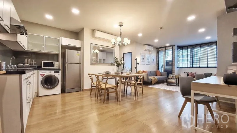 Condominium for rent in Khlong Toei, Bangkok - Open-plan kitchen, dining and living space with stainless fridge, microwave, washing machine and sofa nook.