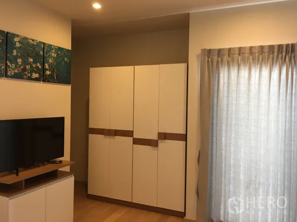公寓 出租在Phaya Thai, Bangkok - 现代公寓客厅，配电视柜、白色衣柜与落地窗帘。