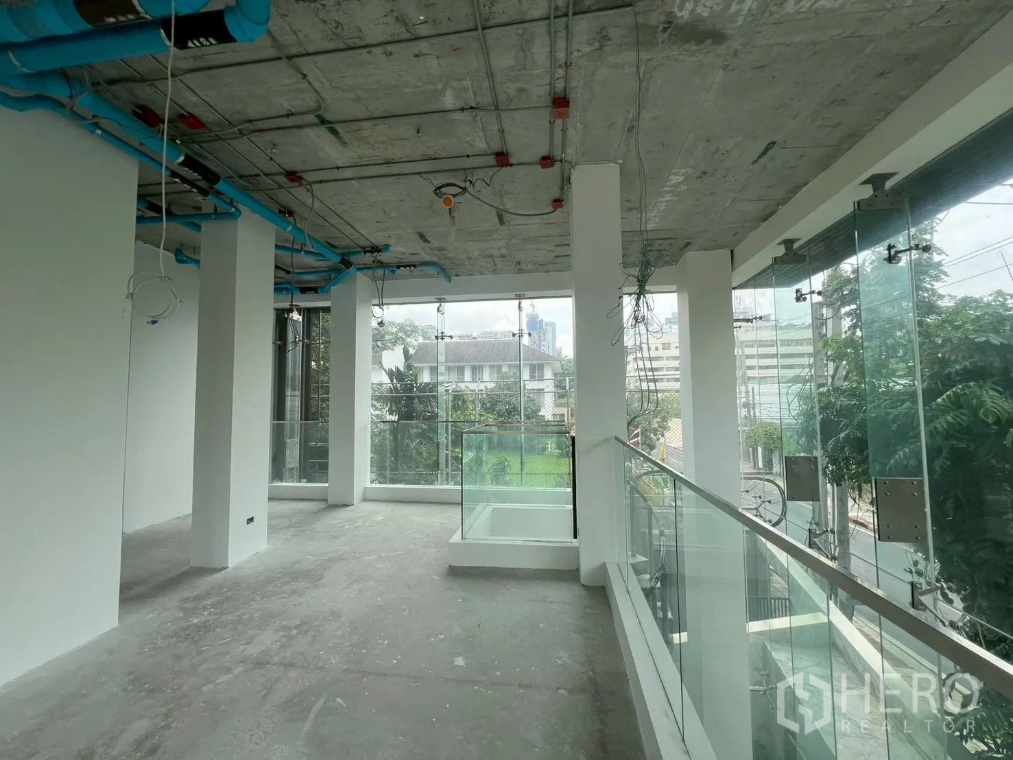 Retail Space for rent - Open-plan upper floor with glass railing overlooking trees and the neighborhood.