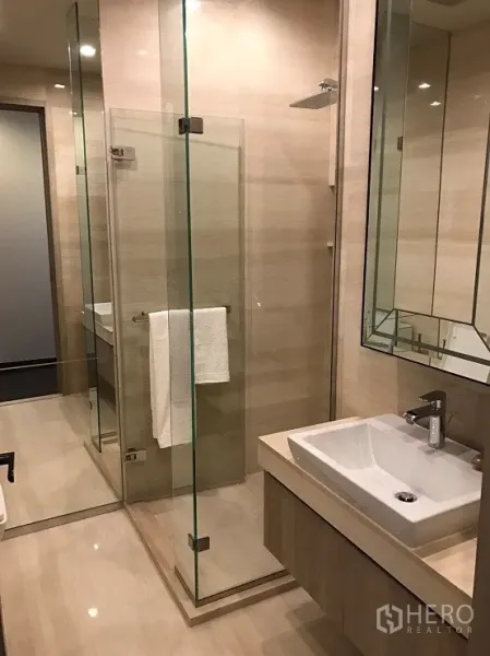 公寓 出租或出售在Watthana, Bangkok - 现代卫浴，玻璃淋浴间、顶喷花洒与方形台盆，色调明亮。
