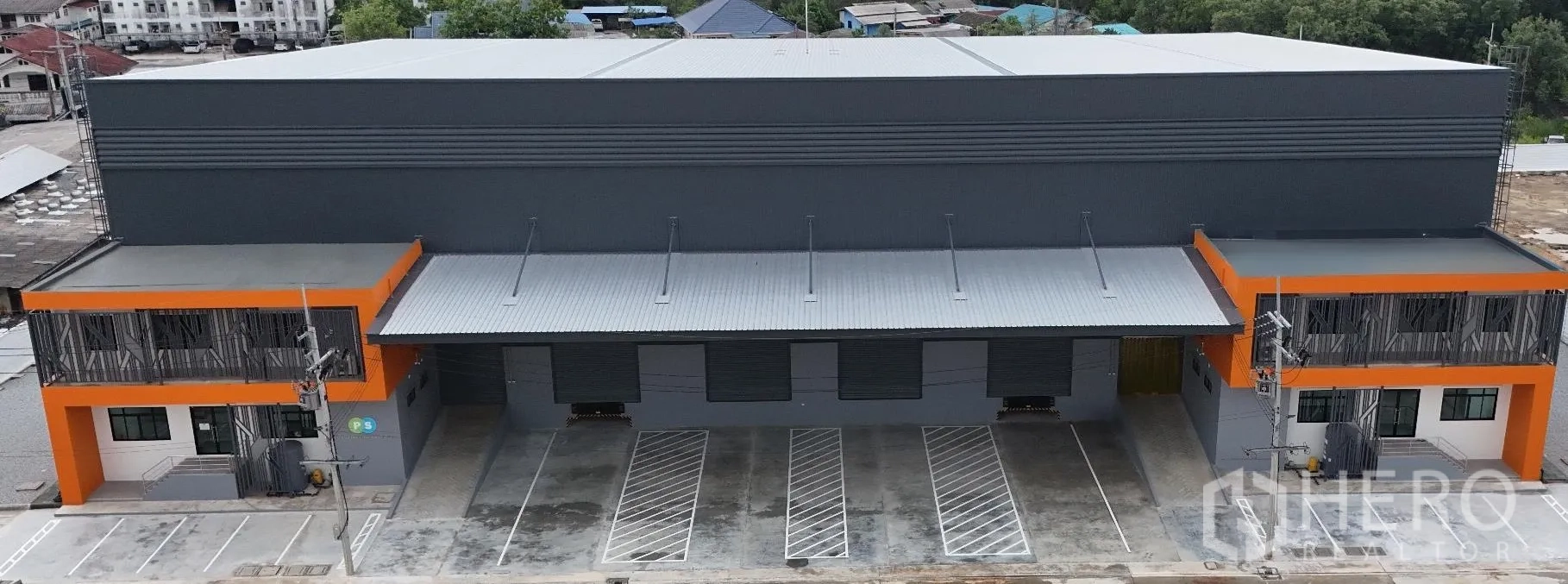 Factory for rent in Bang Sao Thong, Samut Prakan - Modern factory exterior with covered loading dock, multiple roller shutters and marked parking bays.