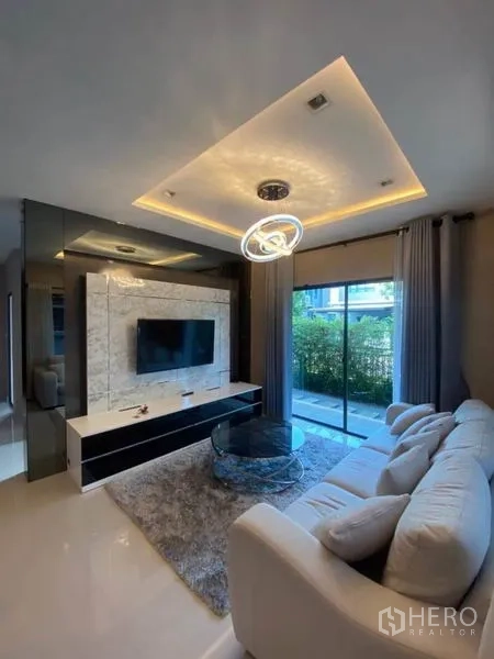 Detached House for rent or sale in Saphan Sung, Bangkok - TV feature wall with marble paneling facing a sofa and garden view.