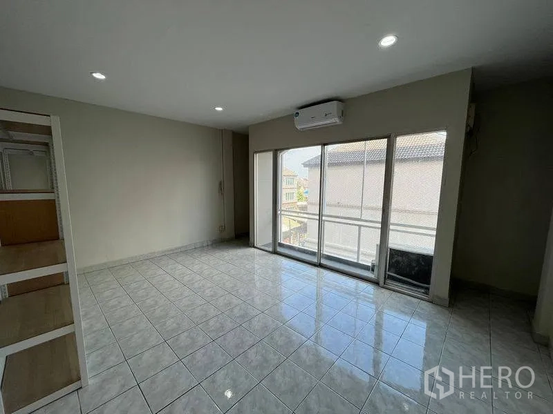 ทาวน์เฮาส์ for rent in Phra Khanong, Bangkok - ห้องปูกระเบื้องสว่าง พร้อมประตูกระจกบานเลื่อนและเครื่องปรับอากาศติดผนัง.