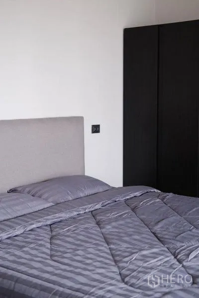 Condominium for rent in Bang Rak, Bangkok - Minimal guest bedroom with gray bedding and a tall black wardrobe.