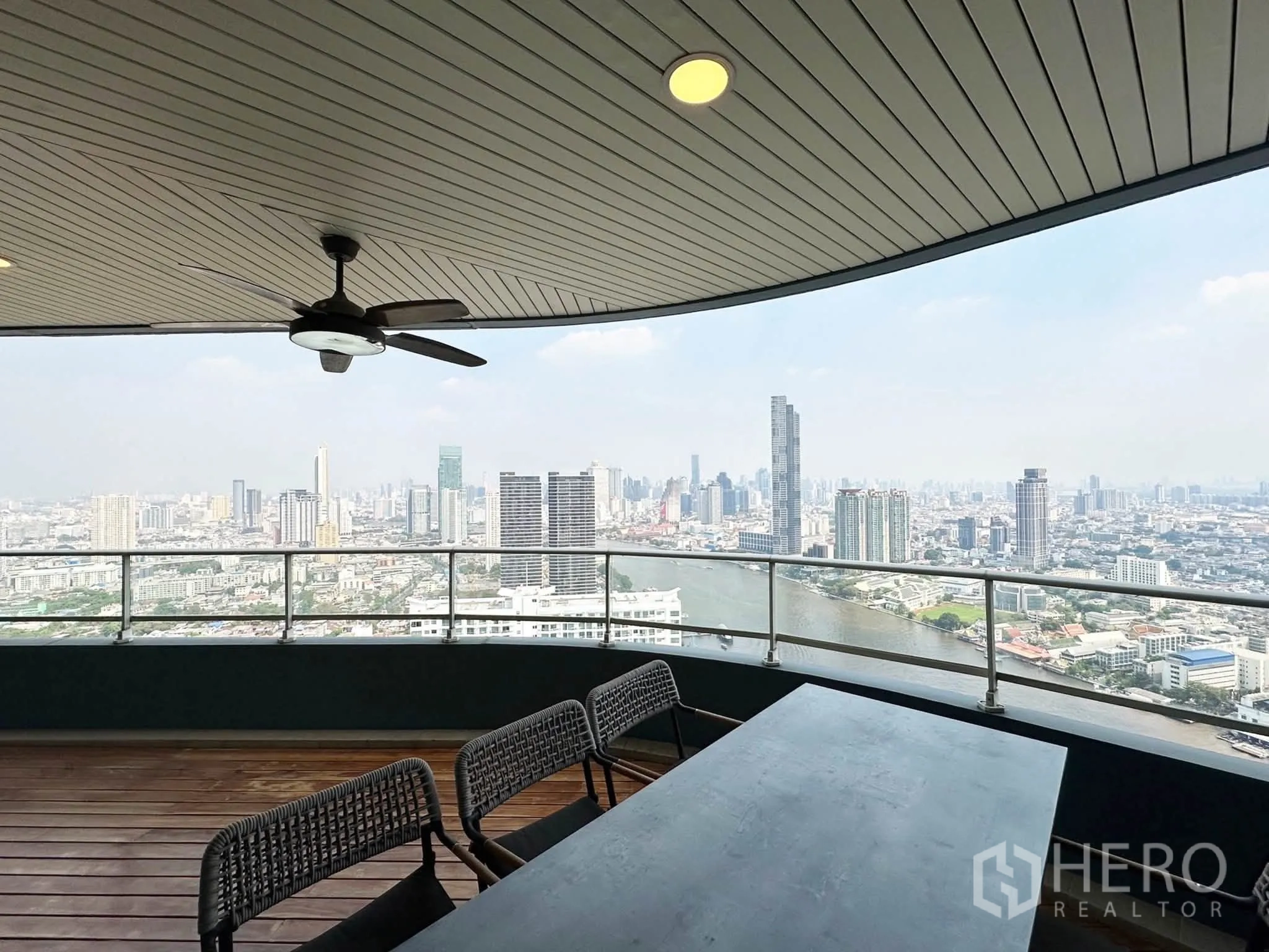 คอนโด for sale in Khlong San, Bangkok - ระเบียงมีหลังคาพร้อมพัดลมและโต๊ะยาว มองชมวิวเมืองและแม่น้ำแบบพาโนรามา