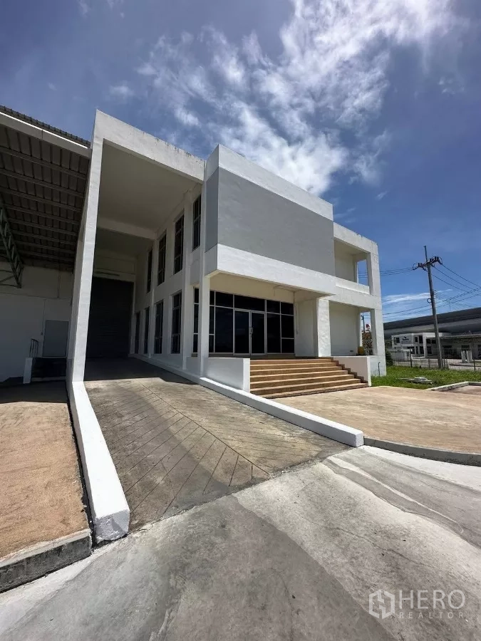 โรงงาน ให้เช่าในSi Racha, Chon Buri - อาคารสำนักงานสองชั้นสมัยใหม่พร้อมทางลาดและบันไดข้างตัวโรงงาน ใต้ท้องฟ้าสีคราม