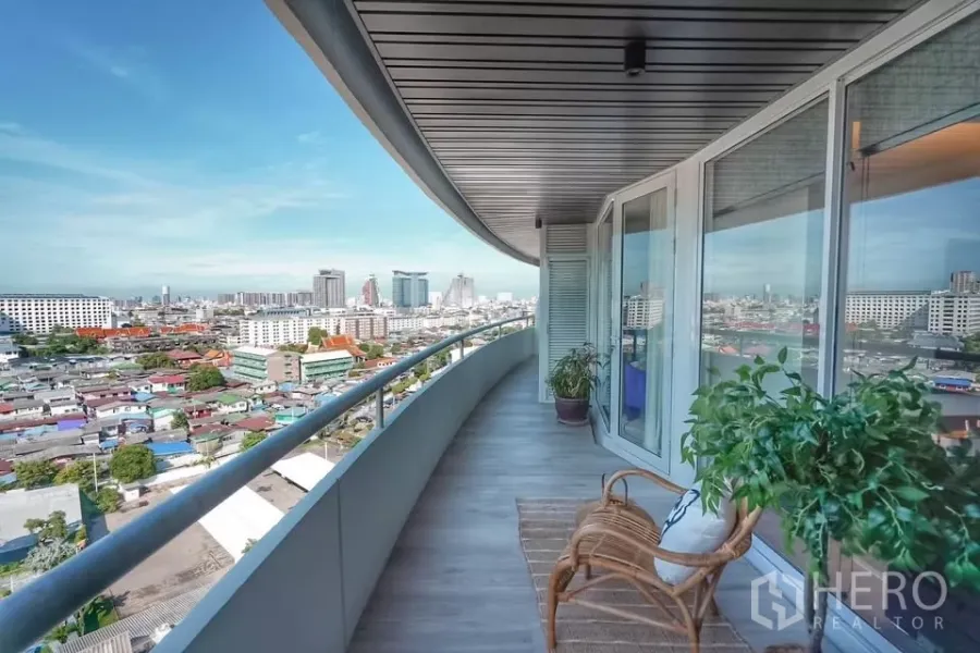 公寓 出租在Bang Phlat, Bangkok - 弧形临河阳台，设休闲椅与绿植，俯瞰曼谷城市天际线全景。