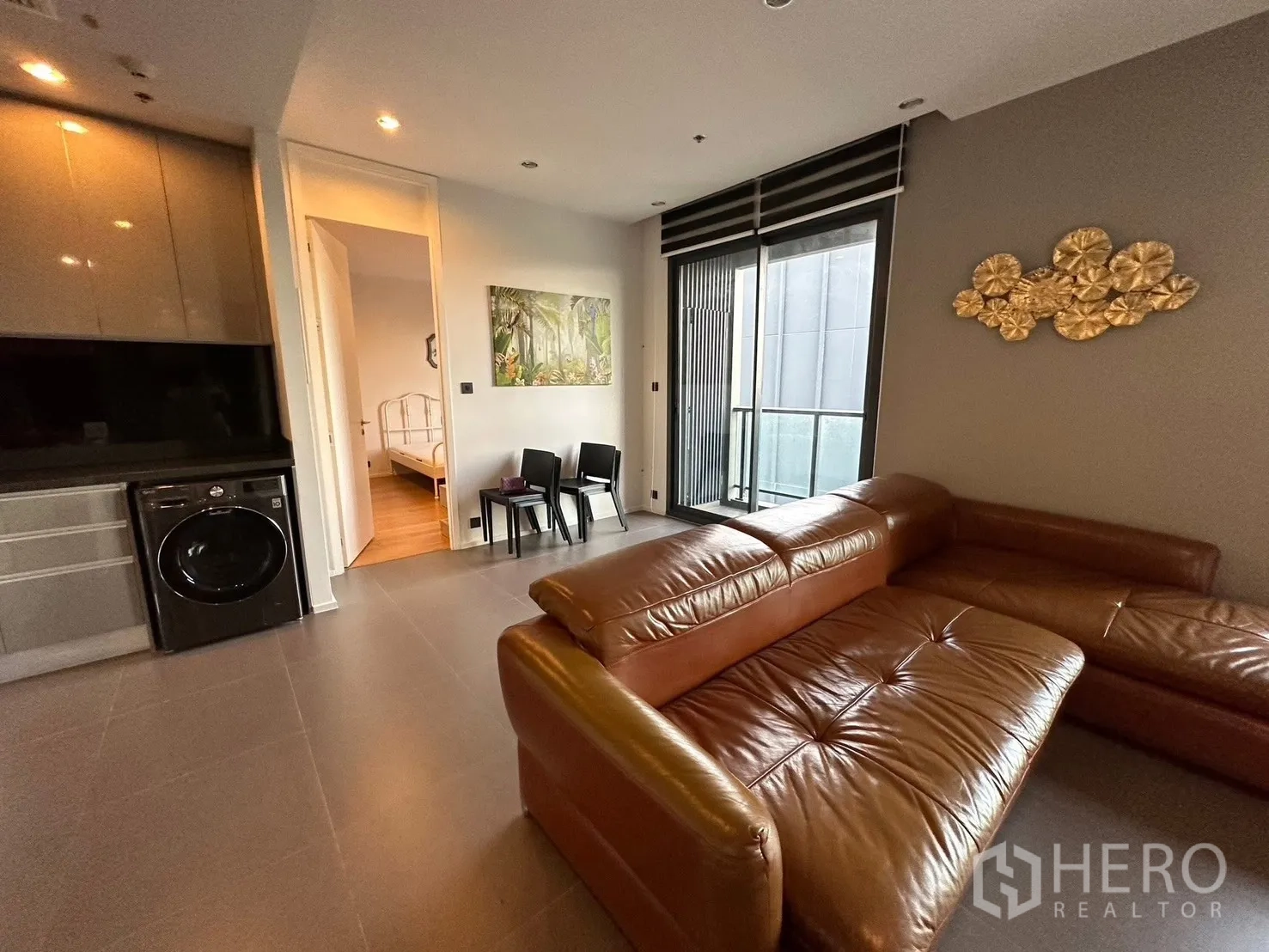 Condominium for rent or sale in Chatuchak, Bangkok - Close-up of L-shaped leather sofa near balcony with city outlook.