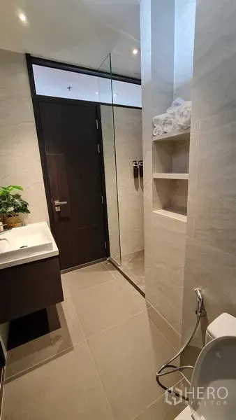 公寓 出租在Watthana, Bangkok - 现代化浴室，玻璃淋浴间、内置置物架与瓷砖地面。