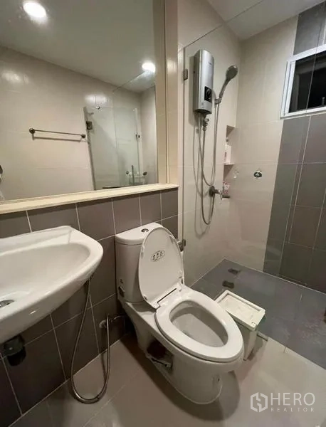Townhouse for rent or sale in Bueng Kum, Bangkok - Bathroom with toilet, vanity, glass-enclosed shower, and water heater.