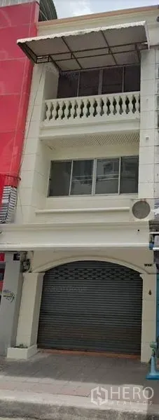 店屋 出租在Watthana, Bangkok - 三层白色店屋外立面，街边卷闸门、阳台与雨棚。