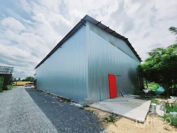 คลังสินค้า ให้เช่าในSam Phran, Nakhon Pathom - ด้านข้างอาคารเมทัลชีท มีประตูสีแดงและทางเดินบริการ