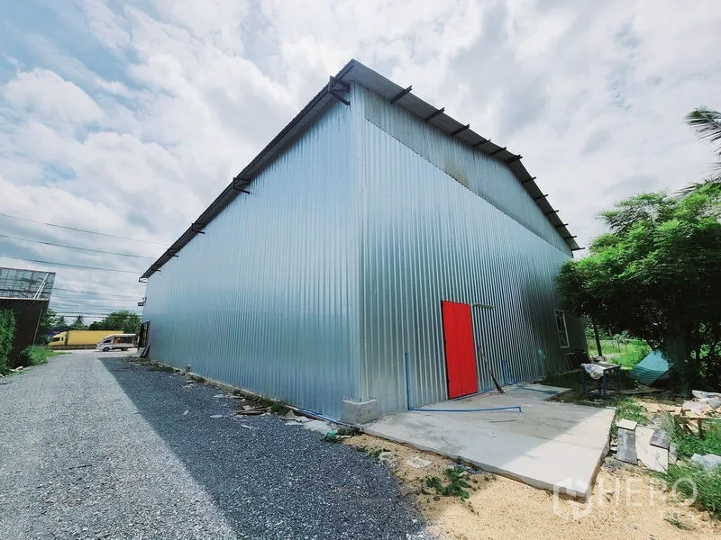 คลังสินค้า ให้เช่าในSam Phran, Nakhon Pathom - ด้านข้างอาคารเมทัลชีท มีประตูสีแดงและทางเดินบริการ