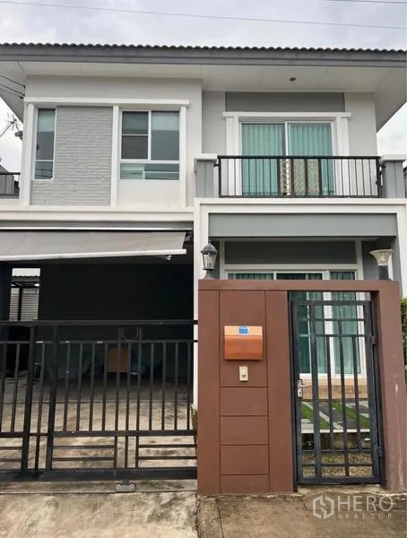บ้าน ให้เช่าในSuan Luang, Bangkok - หน้าบ้านสองชั้นพร้อมรั้วเหล็ก โรงจอดรถ และระเบียง