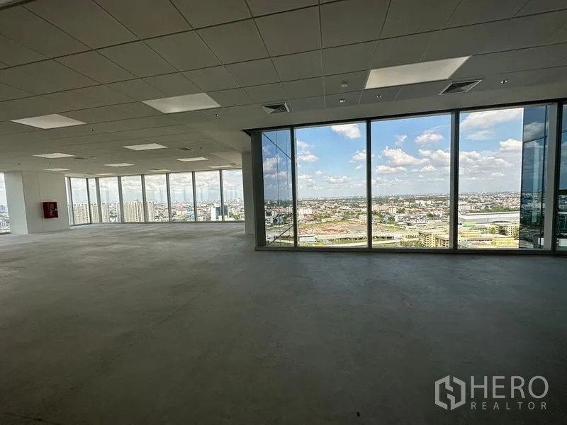 Office Space for rent in Bang Na, Bangkok - Corner office space with floor-to-ceiling glass walls and panoramic city views under recessed lighting in a modern tower.