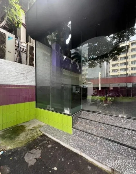 Retail Space for rent in Watthana, Bangkok - Angled exterior of the corner glass facade with tiled plinth and surrounding buildings and trees.