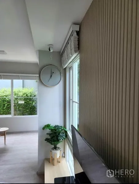 独立式住宅 出租在Prawet, Bangkok - 窗角特写，百叶窗、绿植与挂钟，窗外绿意盎然。