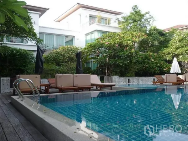 Detached House for rent in Khan Na Yao, Bangkok - Lush garden pool with sun loungers beside modern detached houses in Khan Na Yao