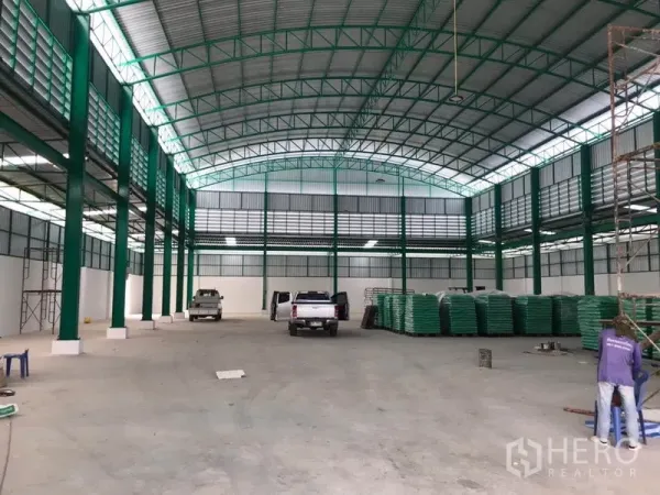 Factory for rent or sale in Mueang Samut Sakhon, Samut Sakhon - Spacious factory floor with green steel frames and high clearance, suitable for production.
