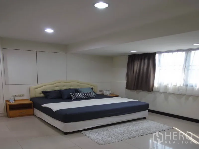 Condominium for rent in Watthana, Bangkok - Modern bedroom with upholstered headboard and soft lighting.