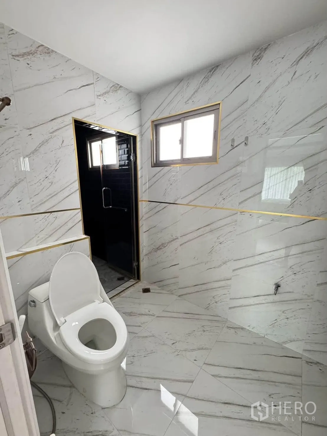 半独立式住宅 for rent or sale in Suan Luang, Bangkok - 现代卫浴采用大理石纹瓷砖，设窗户与深色瓷砖淋浴区。