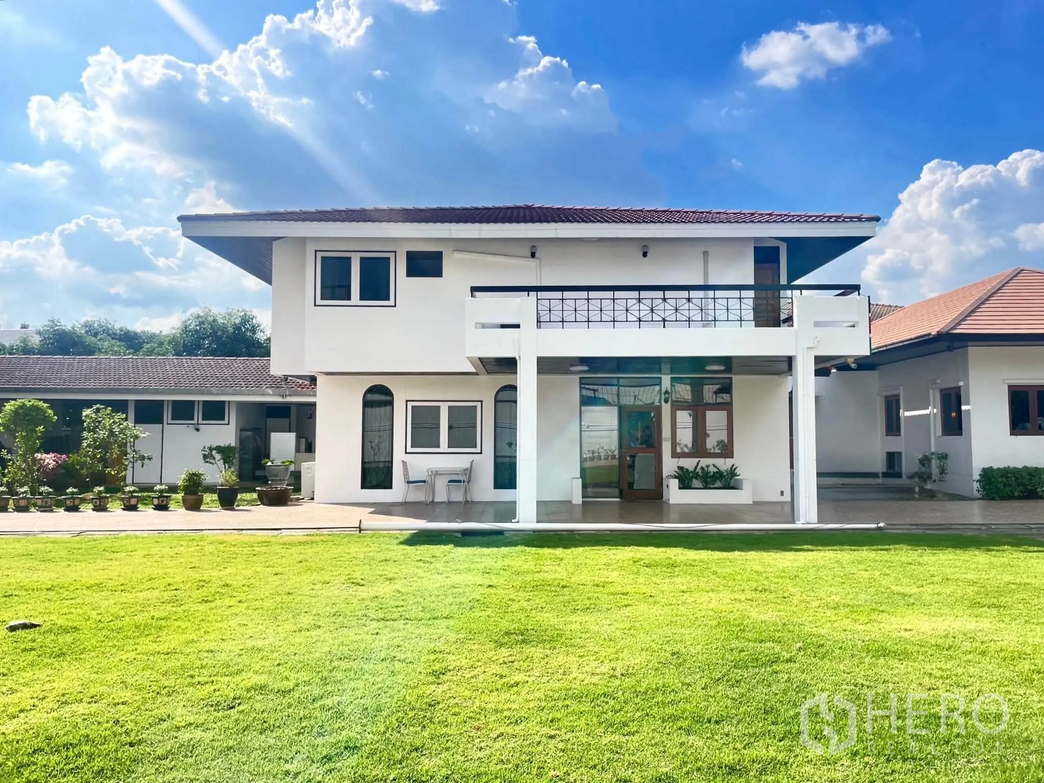 家庭办公室 for rent in Bang Na, Bangkok - 两层白色房屋带阳台，面向宽阔草地。