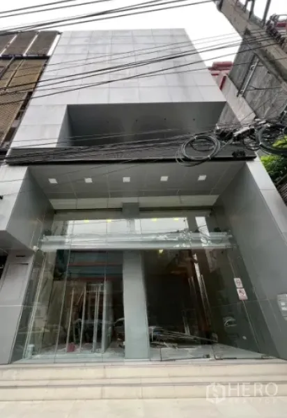 零售空间 出租在Watthana, Bangkok - 现代风零售建筑外立面，整面落地玻璃入口与灰色墙面。