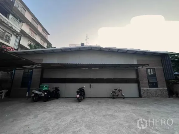 Warehouse for rent in Bang Kapi, Bangkok - Front facade of the warehouse with large sliding doors and forecourt parking area.