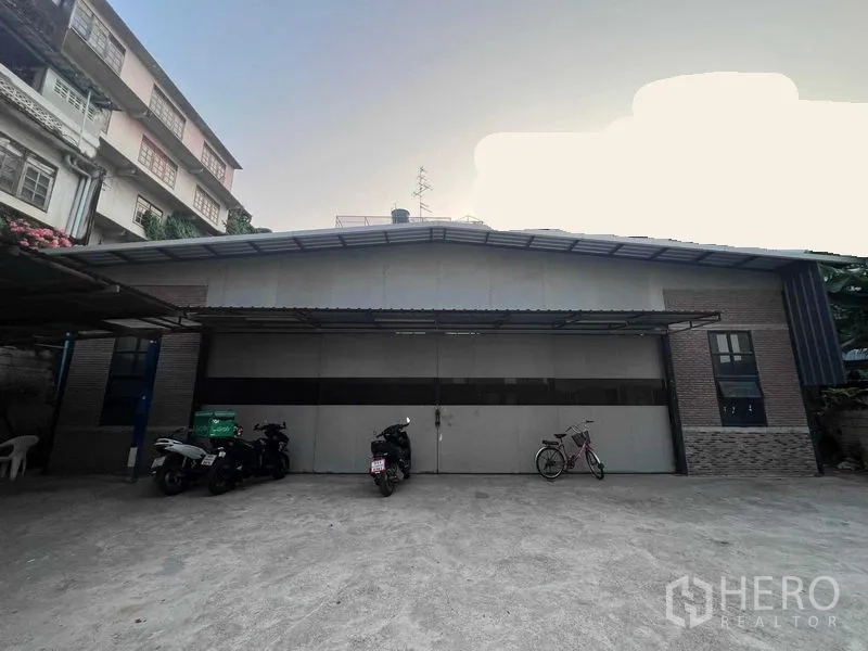 Warehouse for rent in Bang Kapi, Bangkok - Front facade of the warehouse with large sliding doors and forecourt parking area.