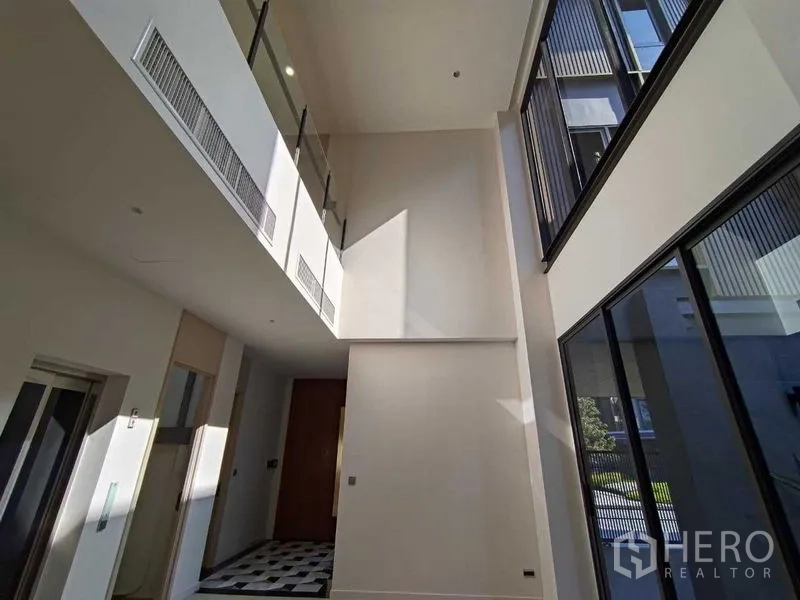 Detached House for rent in Wang Thonglang, Bangkok - Double-height entry hall with floor-to-ceiling windows and a mezzanine railing.