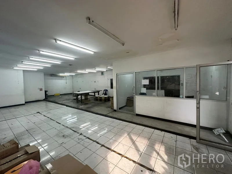 货栈 出租在Khlong Toei, Bangkok - 仓库内明亮的瓷砖工作区，带日光灯照明和玻璃隔断办公室。