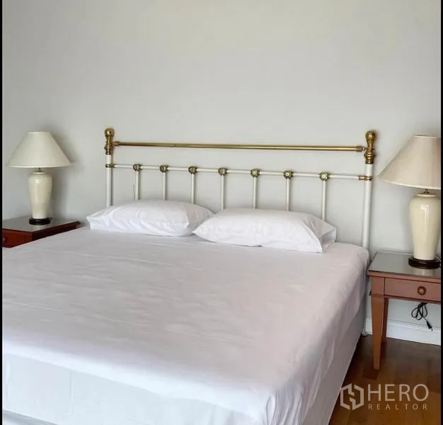 Condominium for rent in Sathon, Bangkok - Master bedroom bed with brass-and-white headboard and matching bedside lamps.