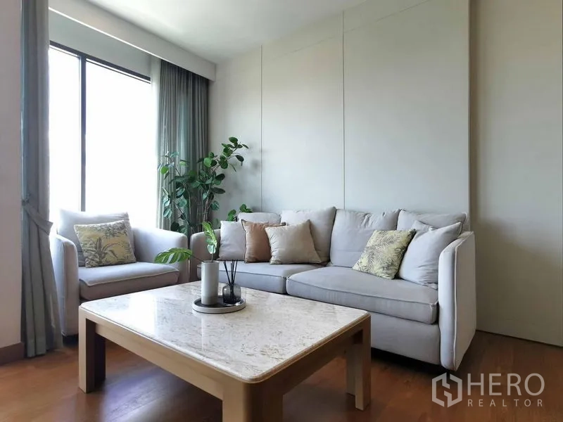 Condominium for rent in Sathon, Bangkok - Cozy secondary lounge with natural light, curtains and a marble-top coffee table.