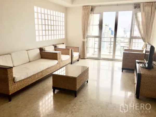 公寓 出租在Khlong Toei, Bangkok - 阳光客厅，藤编沙发，阳台门通向城市景观。